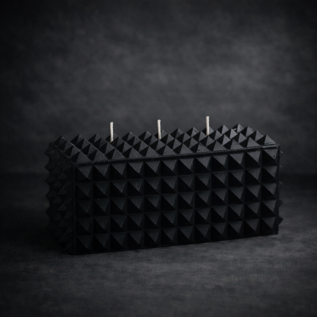 Matte black geometric three wick soy candle with pyramid texture.
