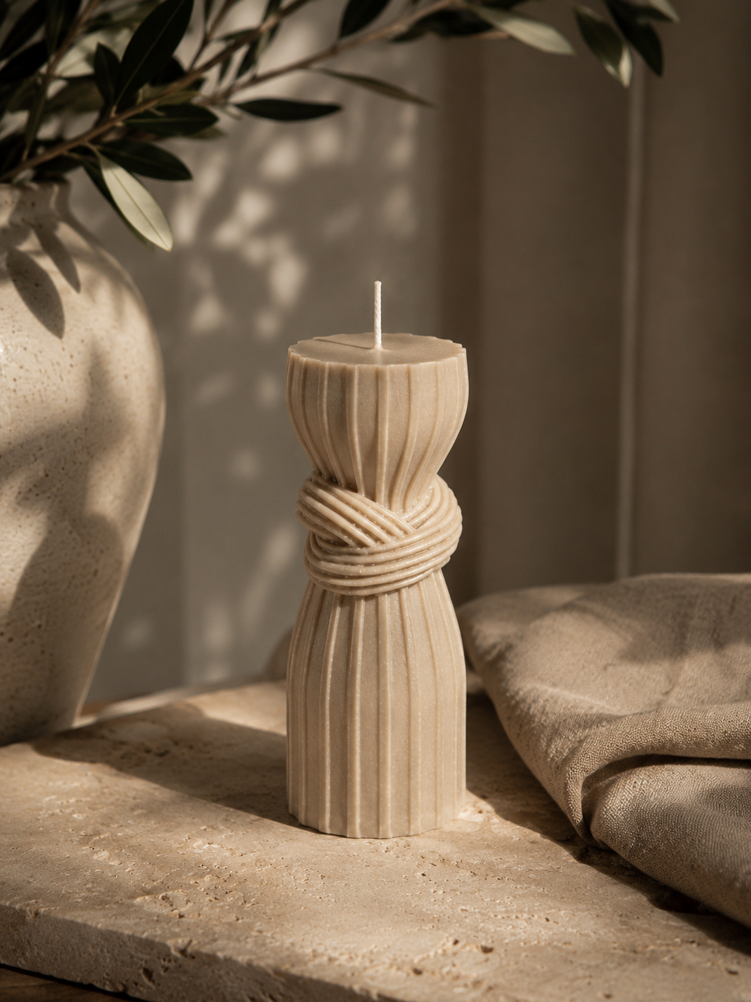 Cashmere Bound Column sculptural candle styled with natural stone and linen in a warm minimalist interior.