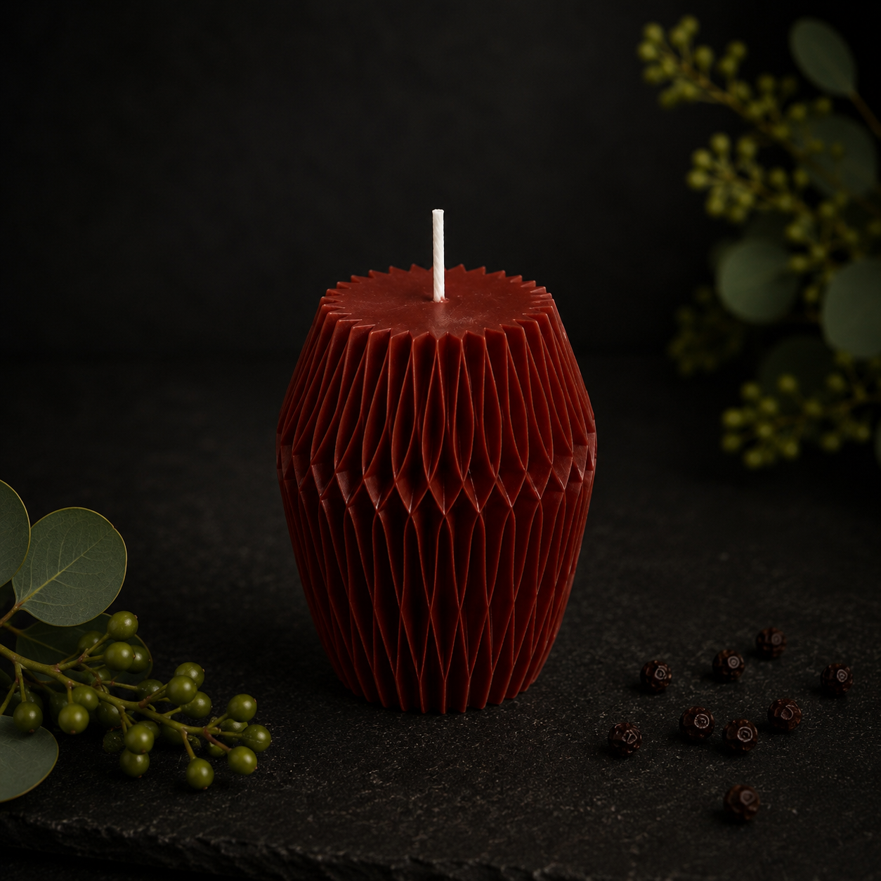 Glow Pantry Ember Facet sculptural candle in a deep ember shade with faceted detailing, styled on a dark botanical backdrop.