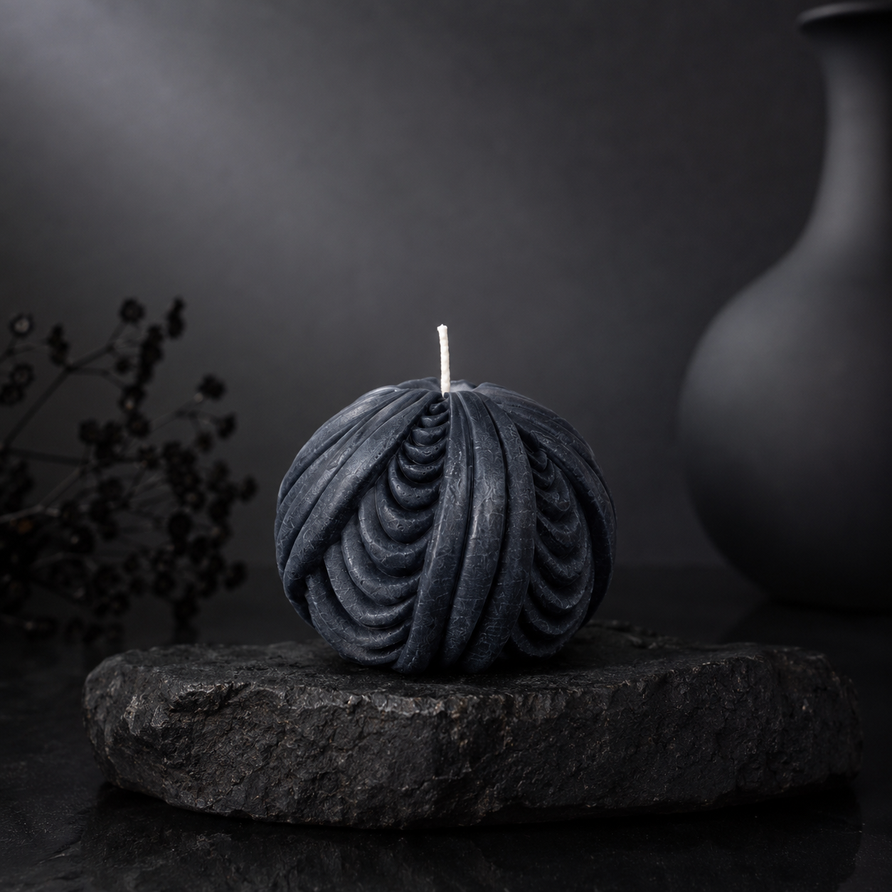 Obsidian Sphere sculptural candle in deep midnight blue displayed on a charcoal stone plinth against a dark editorial backdrop.