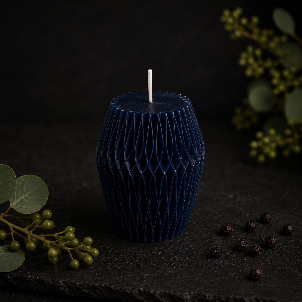 Glow Pantry Midnight Facet sculptural candle in deep midnight blue with faceted detailing, styled against a dark botanical backdrop.