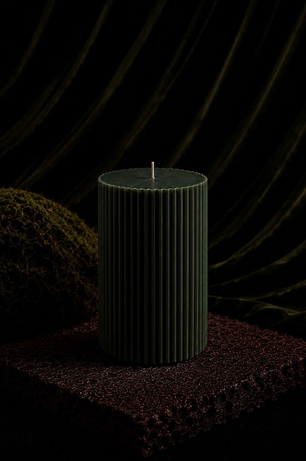 Glow Pantry Atelier Grand sculptural pillar candle in Moss, photographed on a textured stone pedestal against a rich backdrop with soft moody lighting.