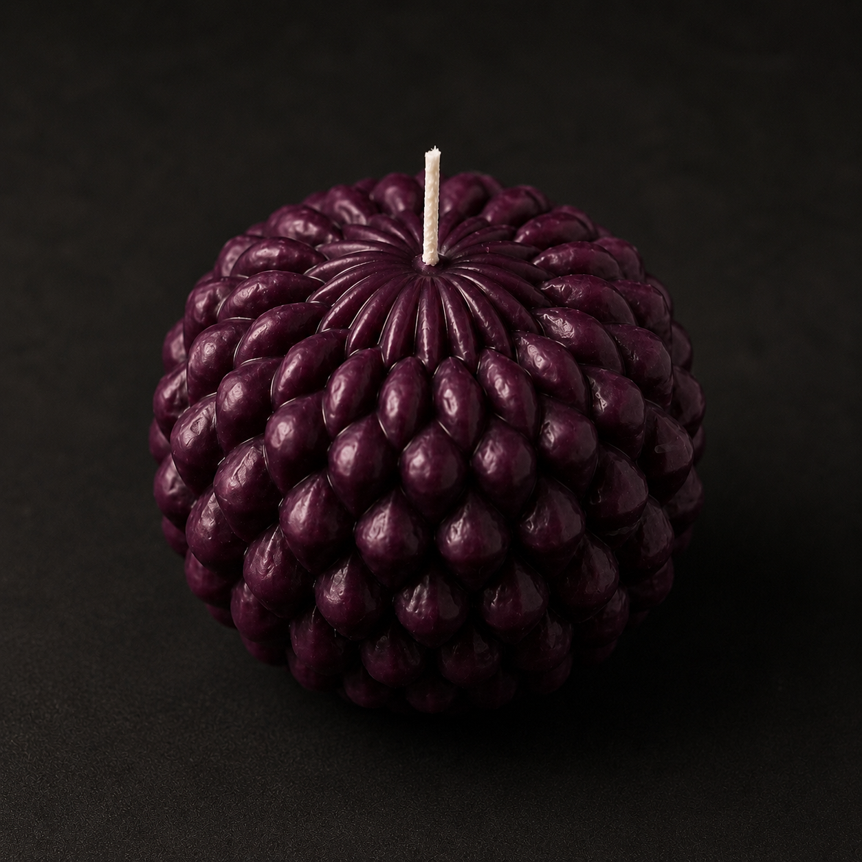 Obsidian Bloom candle in Mulberry, a sculptural petal-formed sphere cast in deep plum wax. Studio-lit against a dark background to emphasise its dimensional texture, moody tones and handcrafted finish.