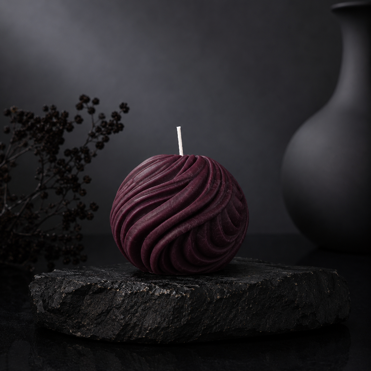 Obsidian Sphere sculptural candle in rich mulberry berry tone displayed on a charcoal stone plinth against a dark editorial backdrop.