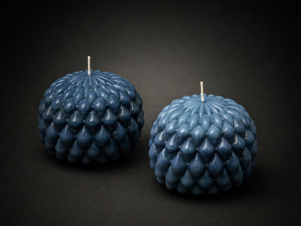 Two Slate Obsidian Bloom sculptural candles with layered petal texture on a dark lowlight background