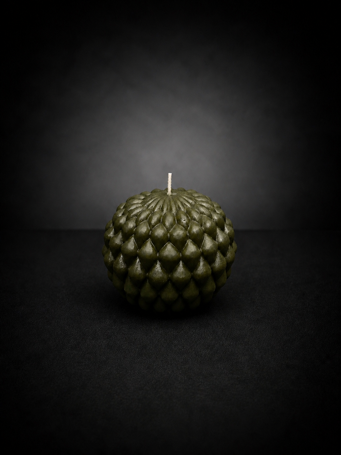 Moss Obsidian Bloom sculptural candle with layered petal texture on a dark lowlight background