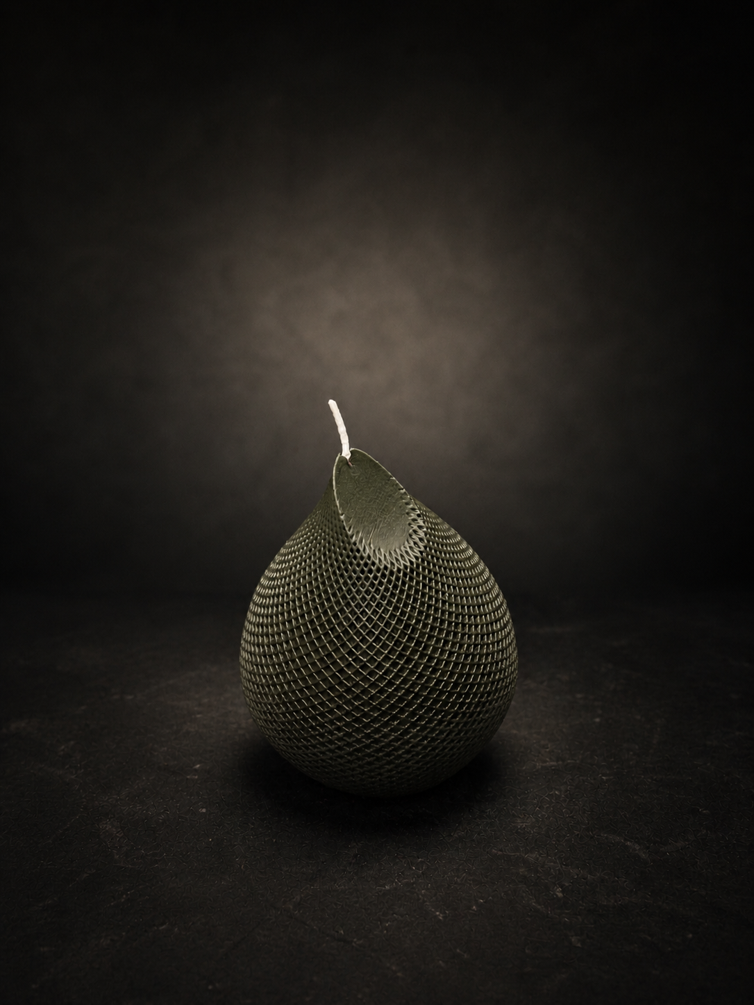 Obsidian Drop candle in Moss — hand-poured deep green sculptural wax piece with textured lattice surface, styled as a moody art object.