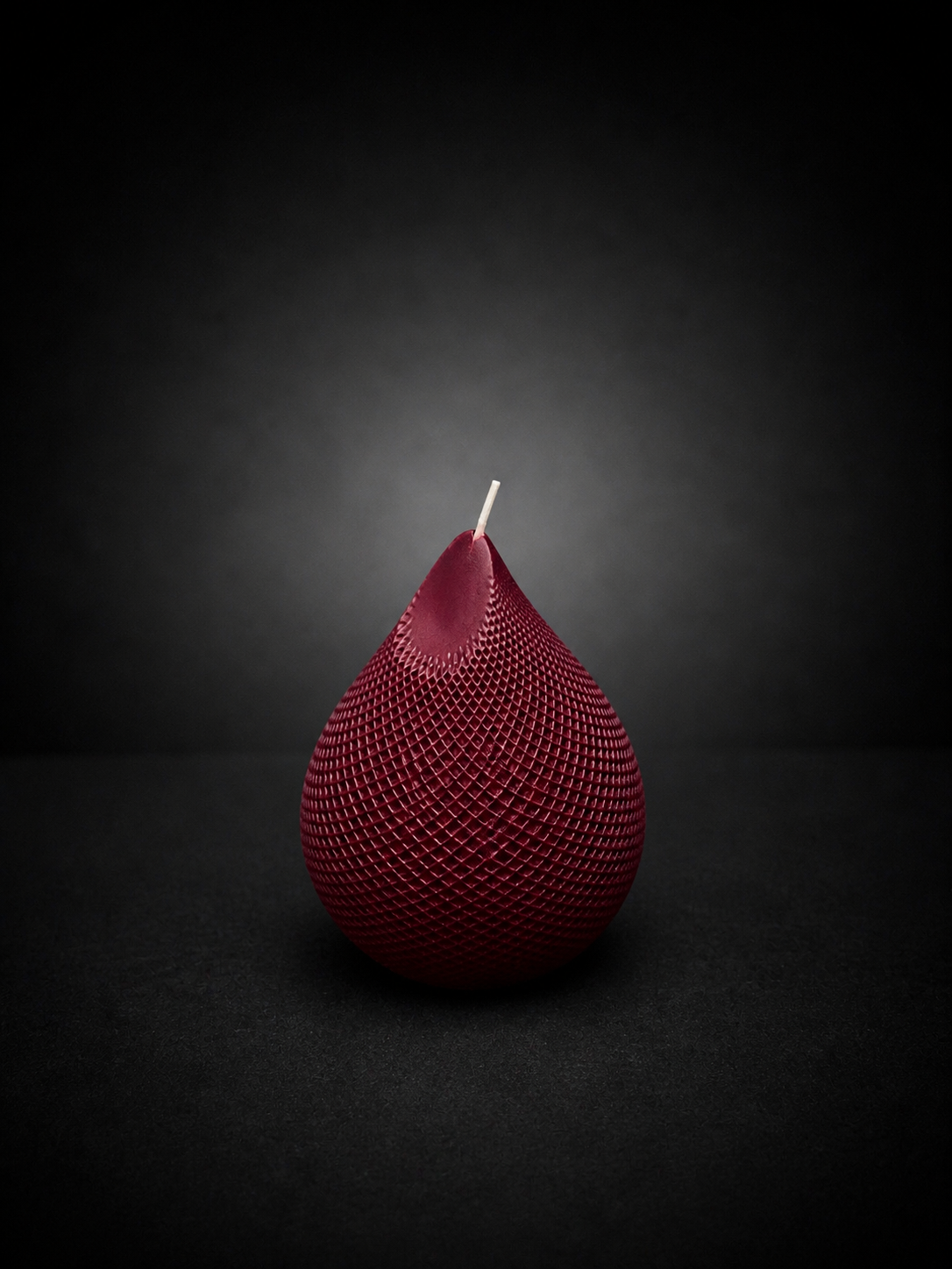 Obsidian Drop candle in Mulberry — hand-poured deep berry sculptural wax piece with textured lattice surface, styled as a moody art object.