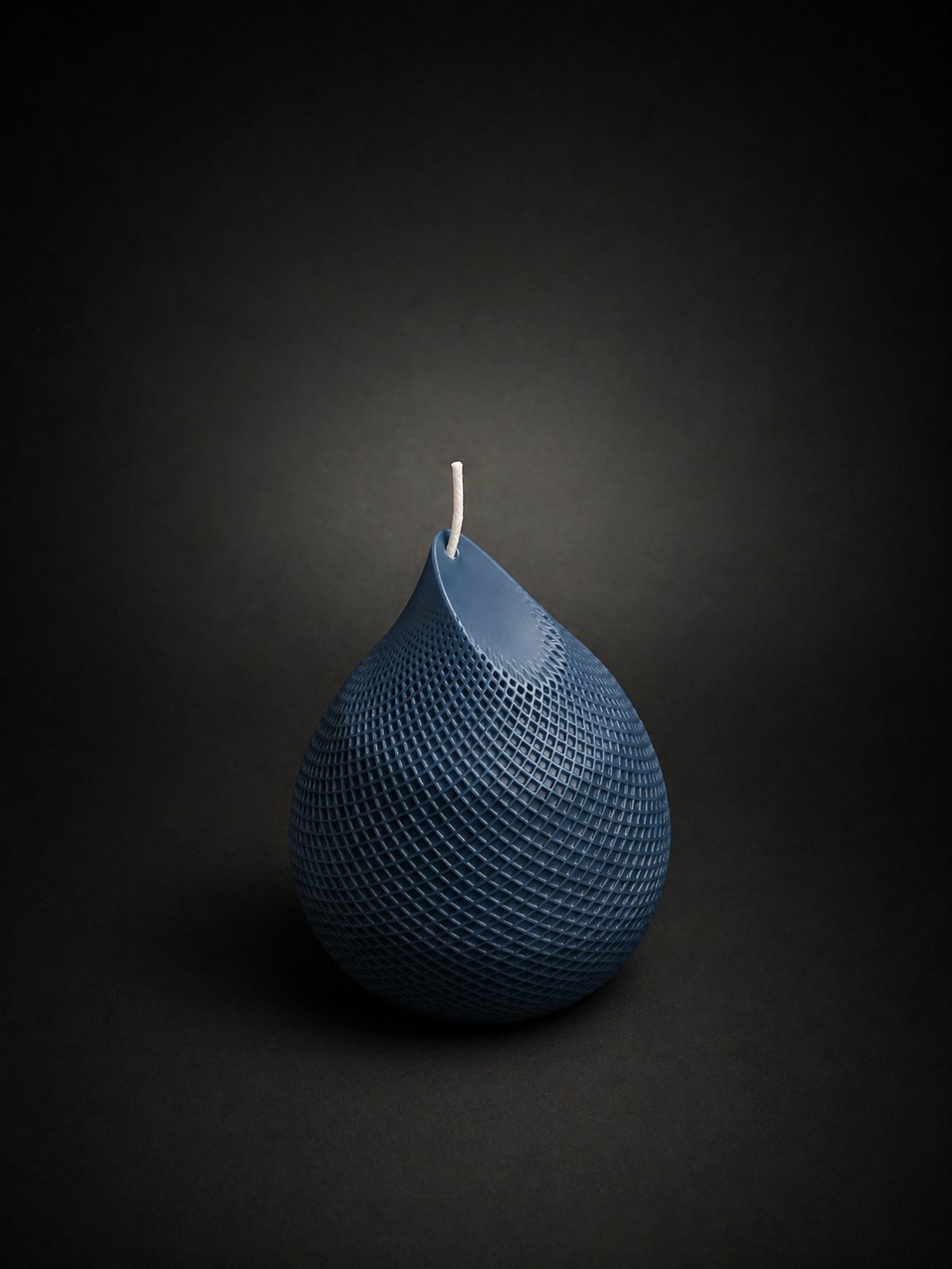 Obsidian Drop candle in Slate — hand-poured deep blue sculptural wax piece with textured lattice surface, styled as a moody art object.
