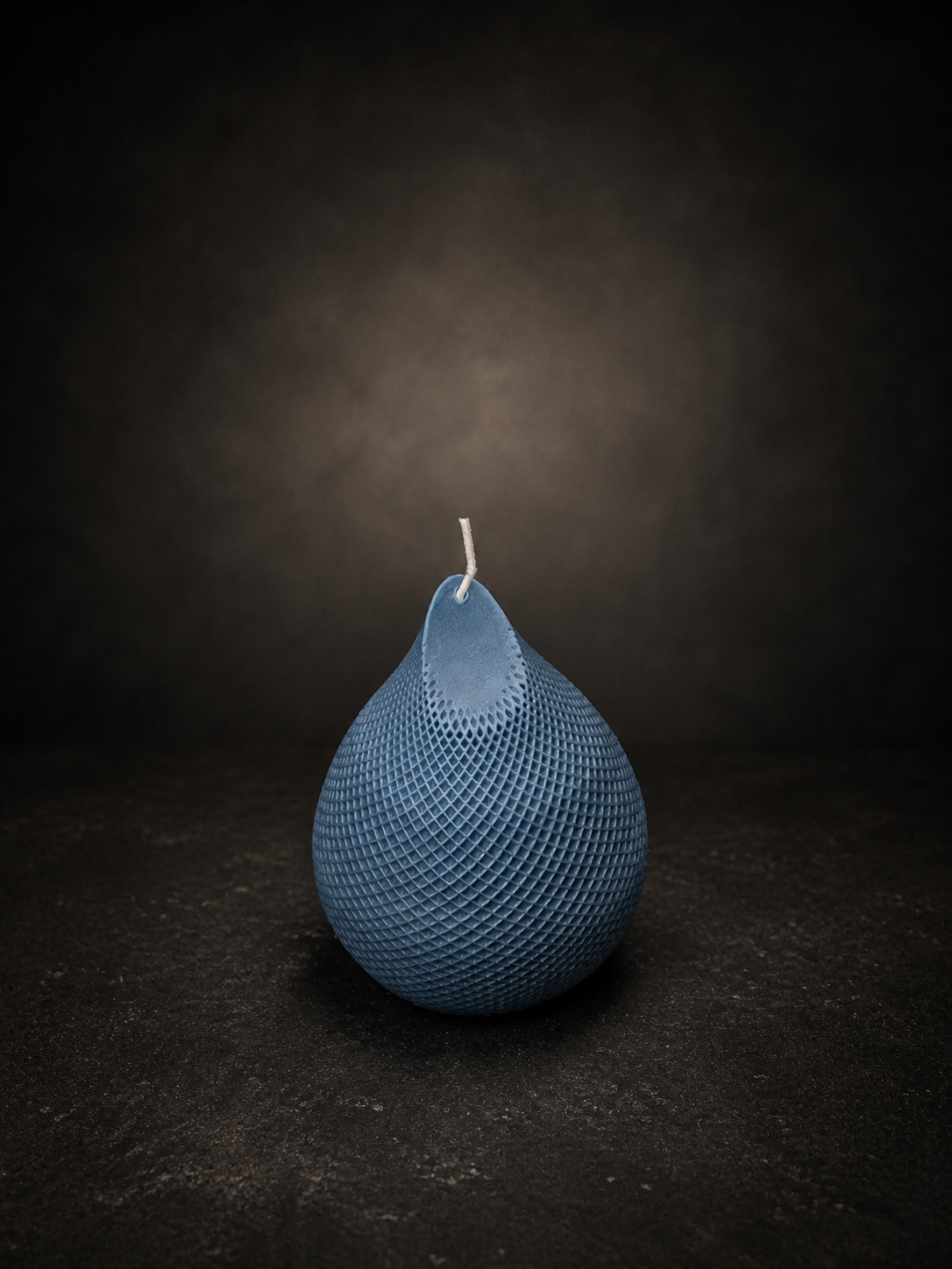 Slate Obsidian Drop candle with textured lattice surface — deep blue sculptural wax form on a dark studio background.