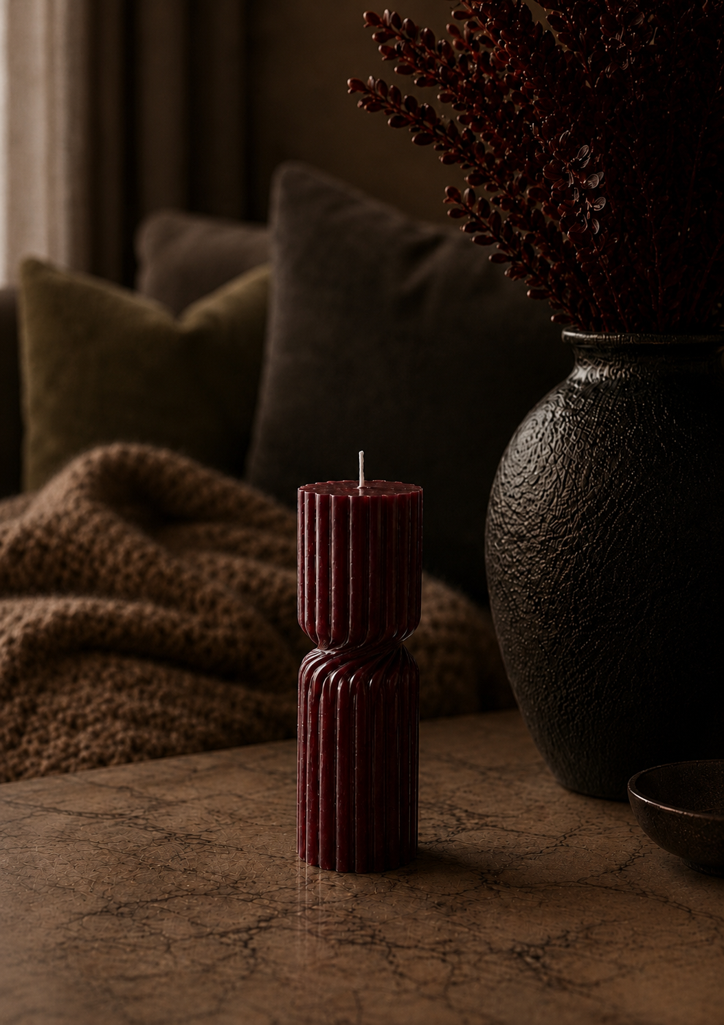 Ember Vestige Column sculptural soy candle styled on a stone table beside a textured black vase in a warm luxury interior.