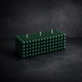 Handcrafted dark green bubble pillar candle with three wicks, photographed on a charcoal studio backdrop.