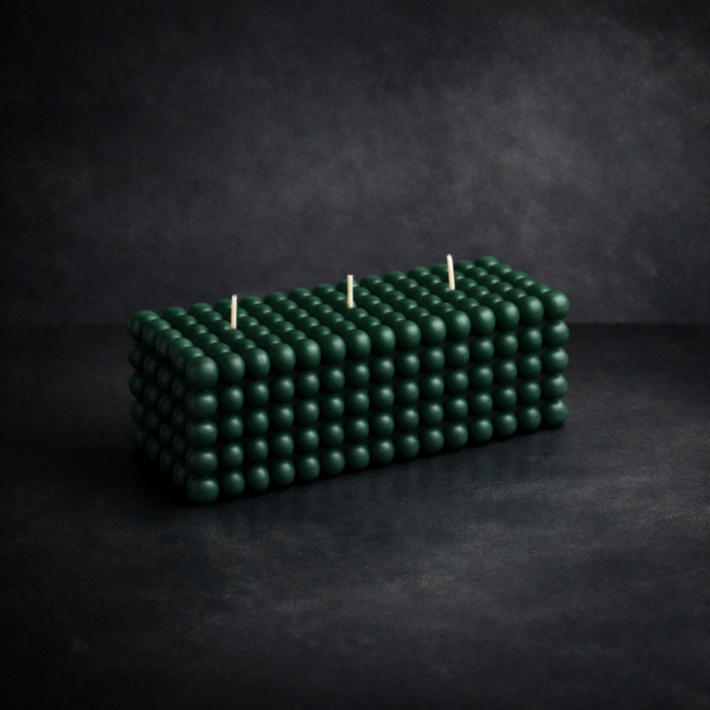 Handcrafted dark green bubble pillar candle with three wicks, photographed on a charcoal studio backdrop.